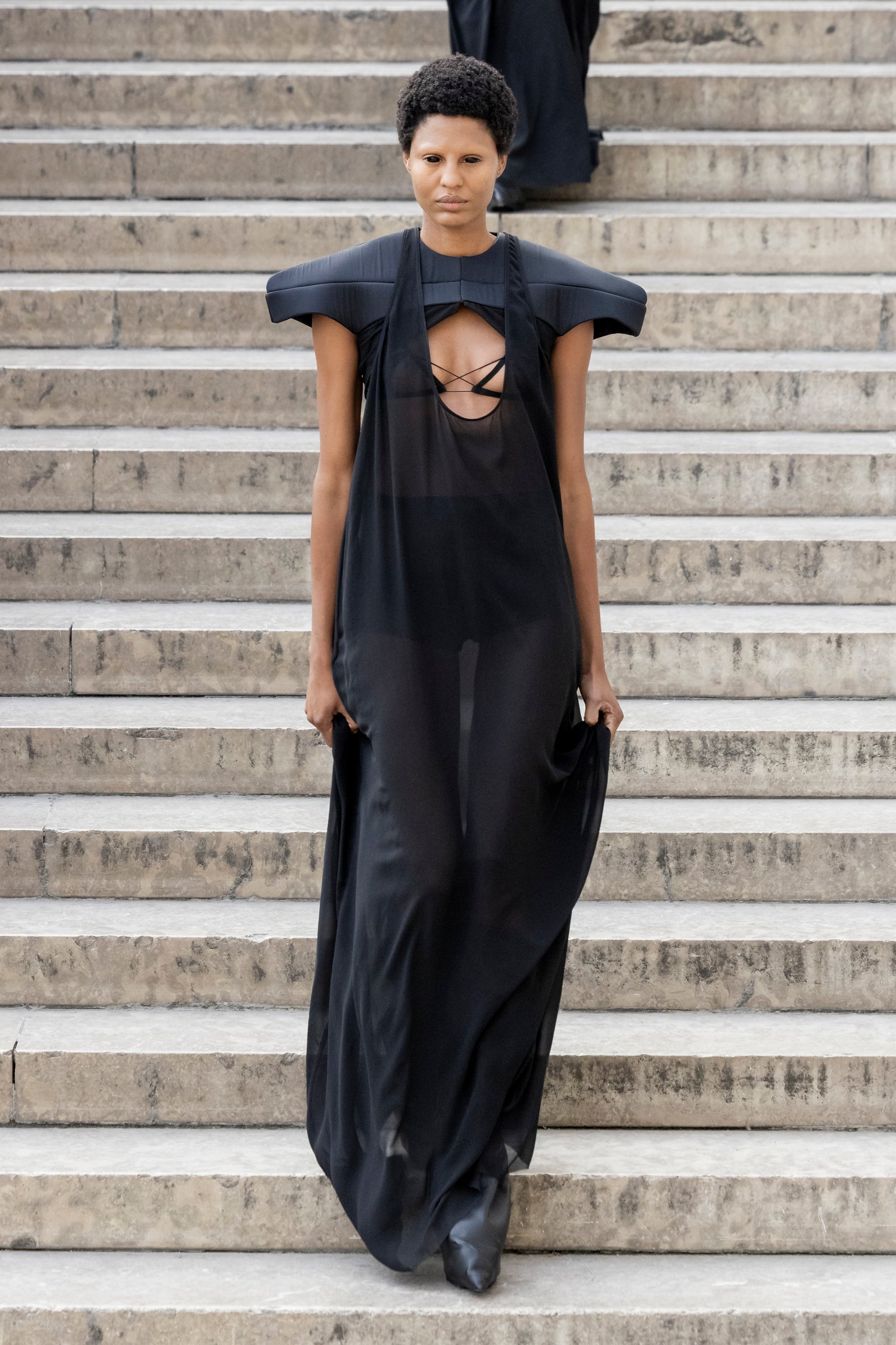 Rick Owens runway look featuring avant garde layered outfit with sculptural silhouette and dark tonal styling