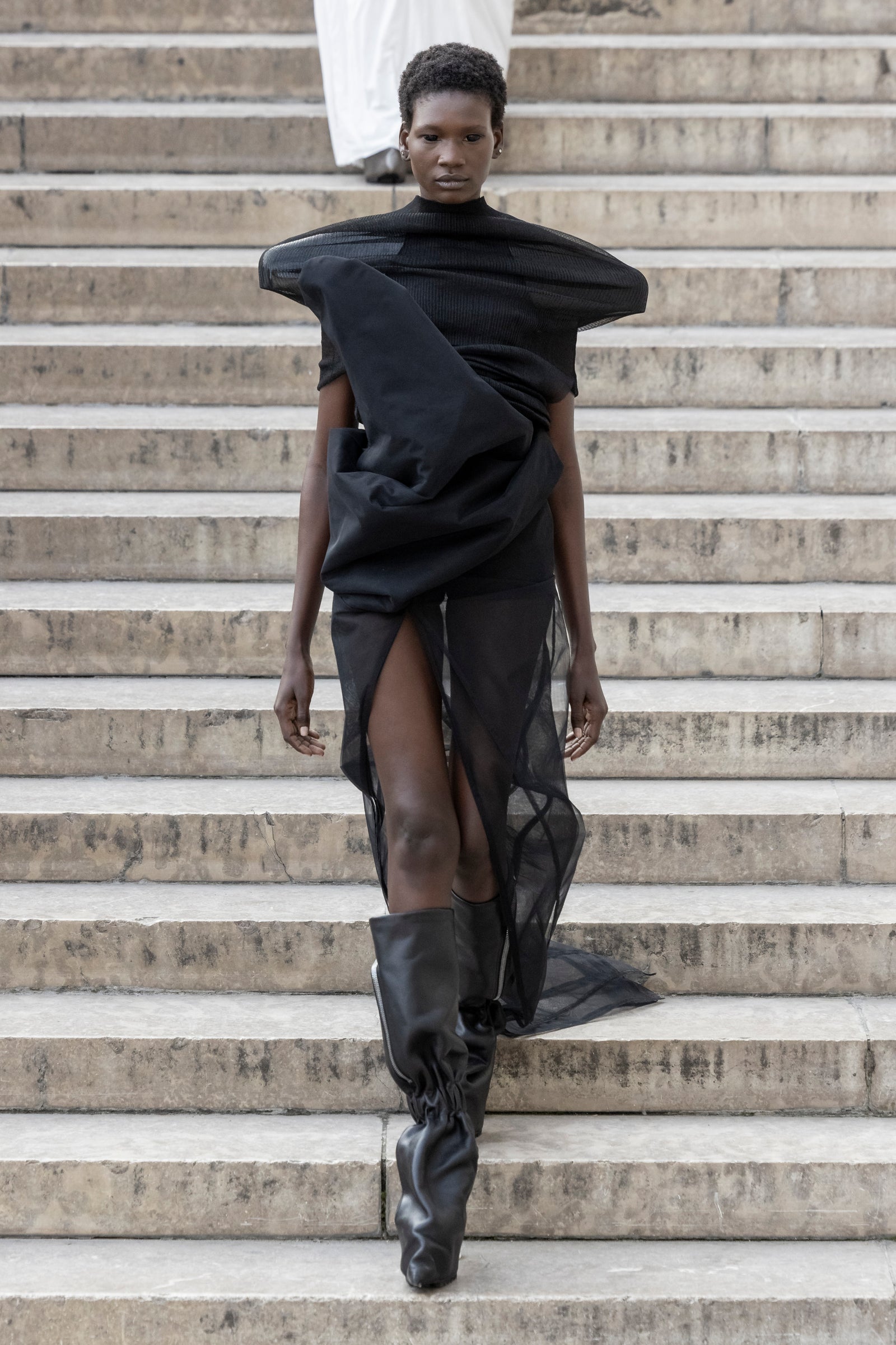 Rick Owens runway look featuring avant garde layered outfit with sculptural silhouette and dark tonal styling