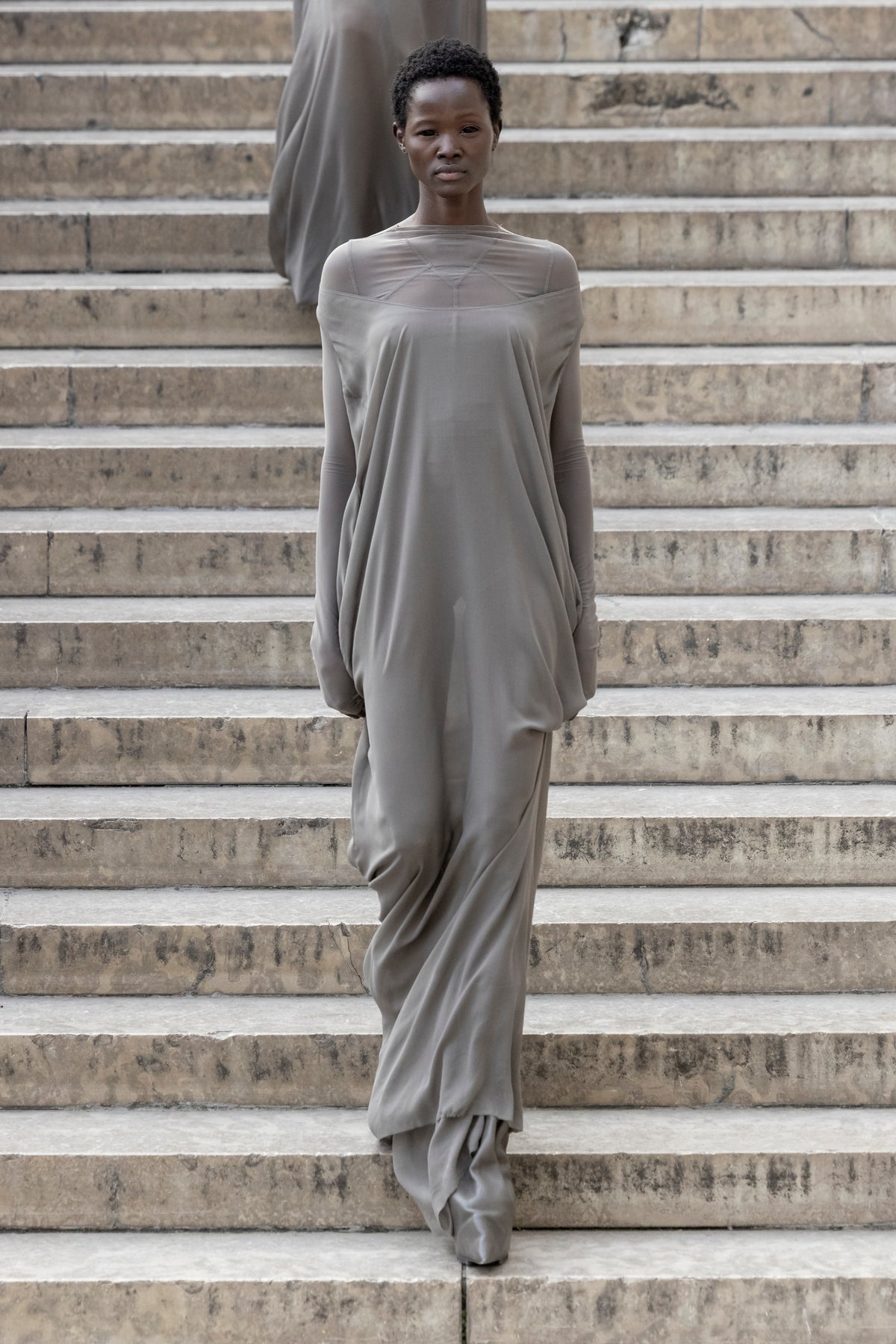 Rick Owens runway look featuring avant garde layered outfit with sculptural silhouette and dark tonal styling